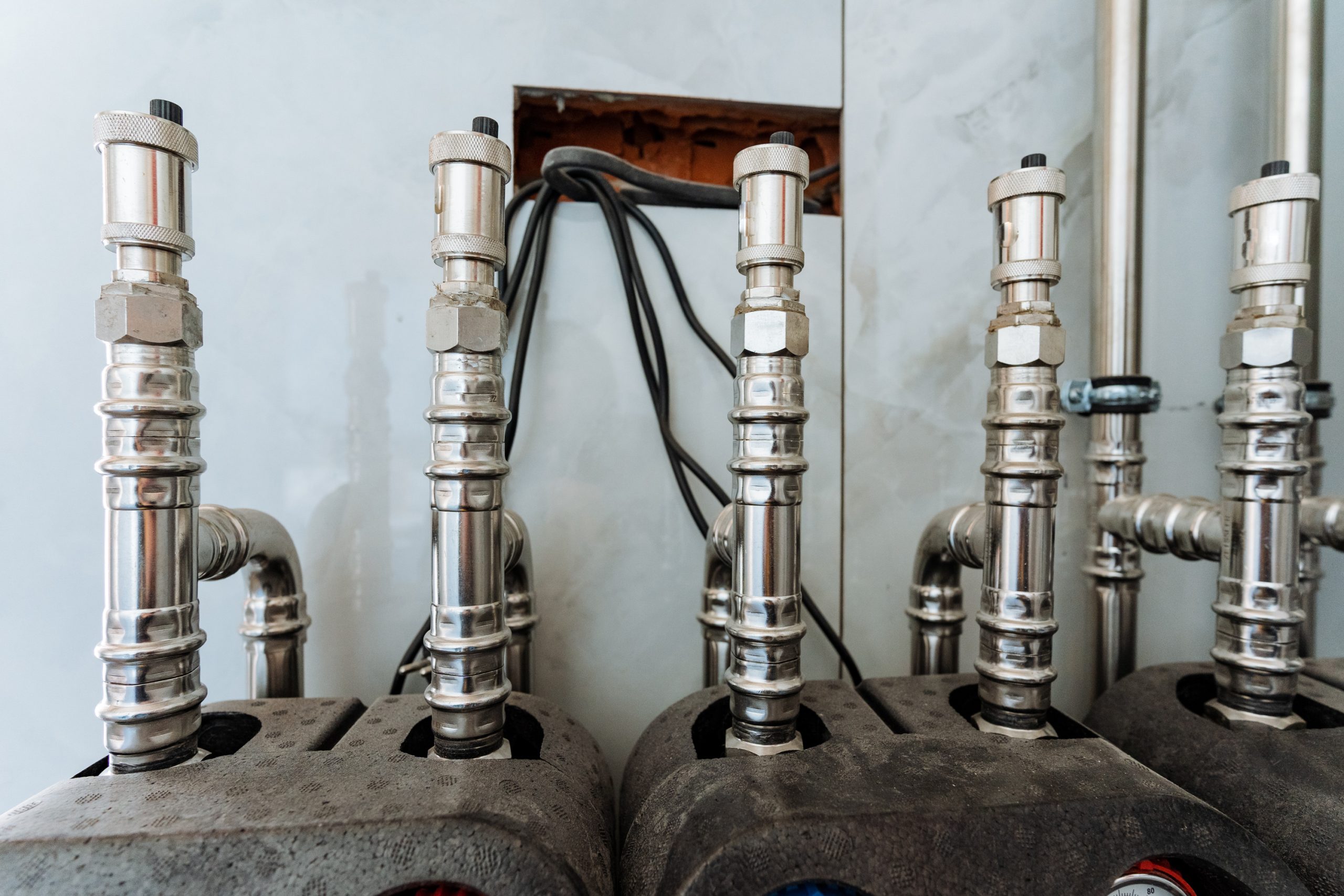 shiny polished stainless steel pipes are securely fixed to a sturdy wall highlighting their robust design versatility and vital role in plumbing and engineering applications free photo